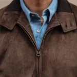 Close-up of a brown suede jacket worn over a striped shirt
