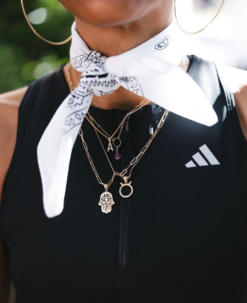 Black athletic top with white bandana and layered gold necklaces