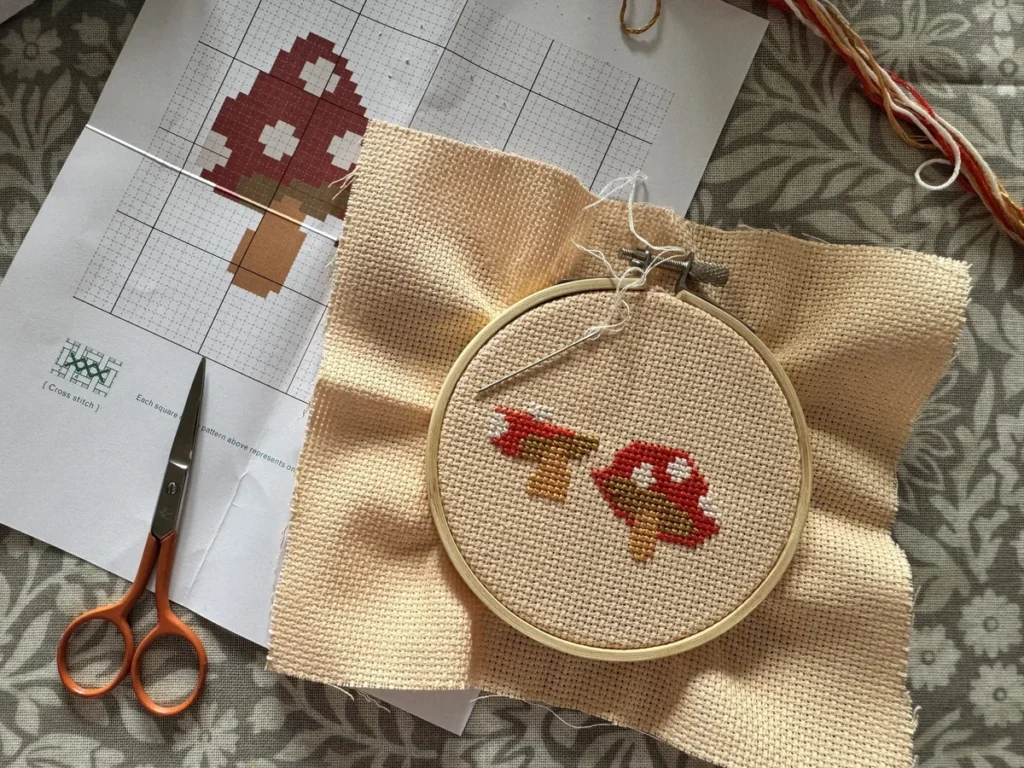 Cross-stitch toadstool embroidery in progress on linen fabric