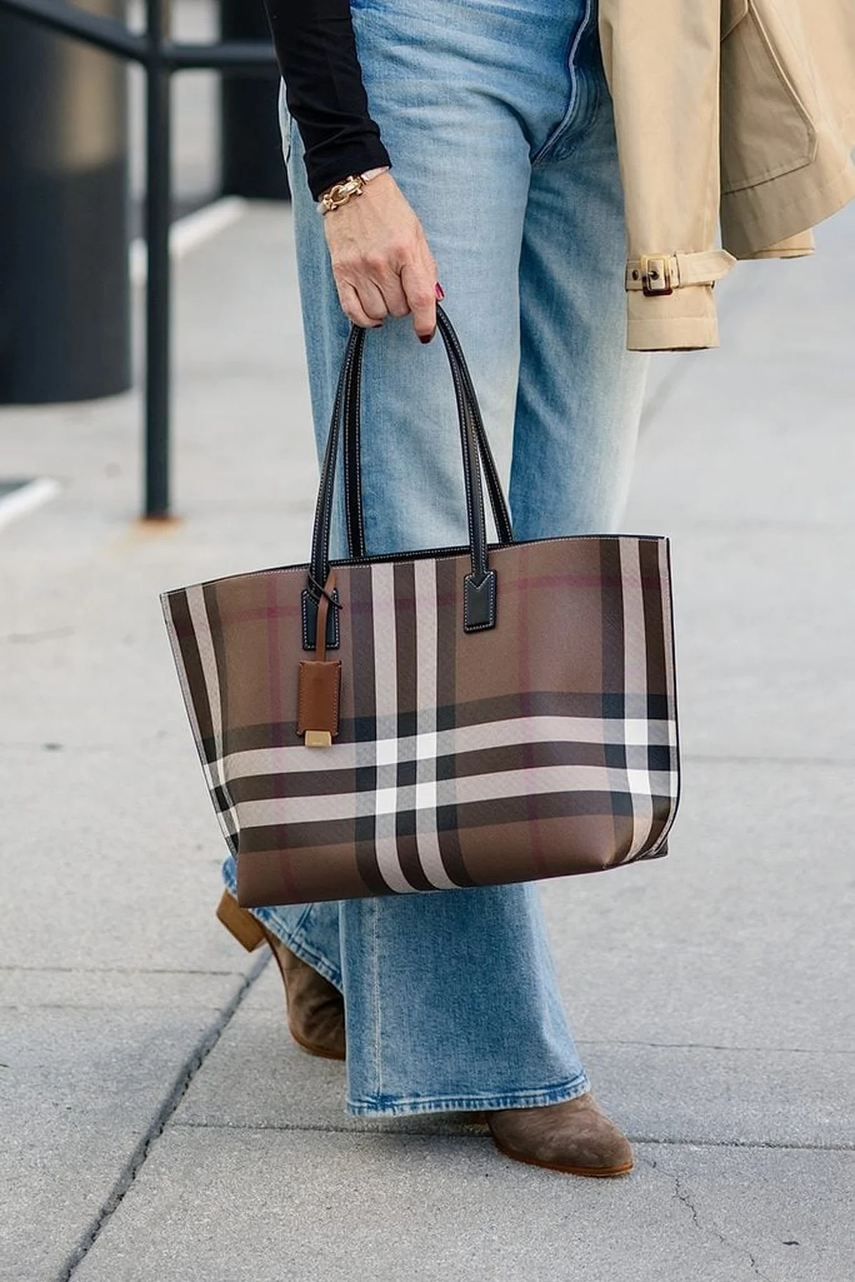 Woman in black top and jeans carrying a plaid check tote
