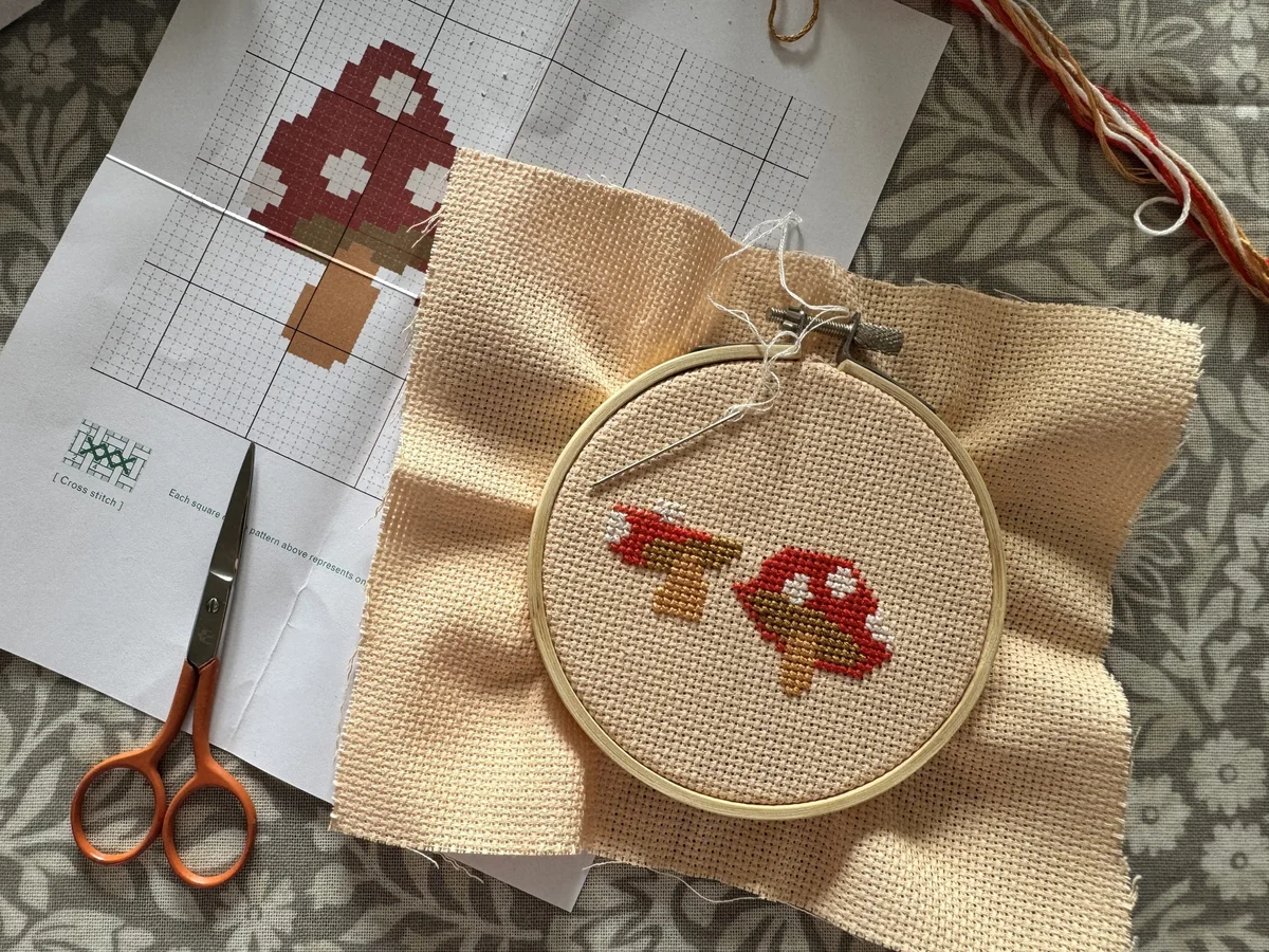 Cross-stitch toadstool embroidery in progress on linen fabric